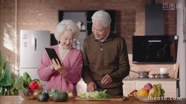 老年夫妇边看平板电脑边做饭